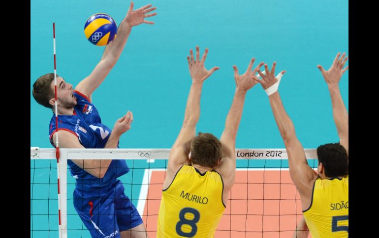 Nikola Kovacevic de Serbia (I) 'pica' a Murilo Endres (C) y Dos Santos Junior durante un bloqueo en el partido del torneo. AFP  /