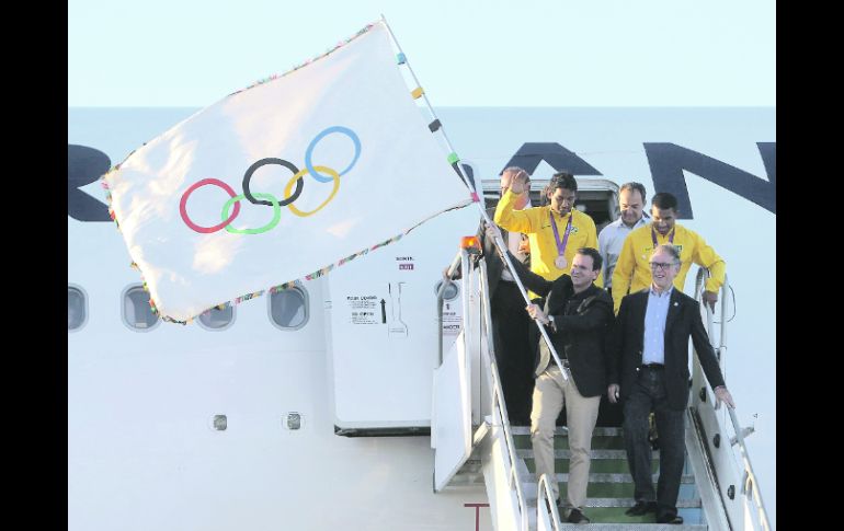 Eduardo Paes, alcalde de Río de Janeiro, desciende con la bandera del COI, acompañado por medallistas brasileños. EFE  /
