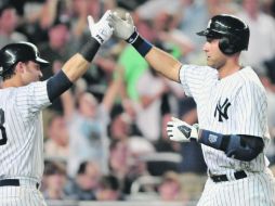 El capitán. Derek Jeter es felicitado por Nick Swisher, tras conectar su batazo sin corredores en los senderos. AFP  /