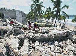 BÚSQUEDA DE VÍCTIMAS. Rescatistas trabajan sobre un hotel derrumbado a la orilla de la playa.  /