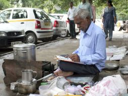Laxman Rao despacha té sentado a ras de suelo en una calle de Nueva Delhi, donde aprovecha para vender también sus obras literarias.EFE  /