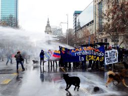 Unos estudiantes intentan protegerse de un carro lanza-agua de la policía, durante una manifestación por la educación en Chile. EFE  /