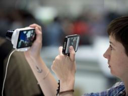 Un visitante usa su celular para tomar una foto a una cámara en exposición en la IFA. AFP  /