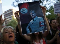 Manifestantes sotienen una imagen con una sátira de la canciller alemana, Angela Merkel. ARCHIVO  /