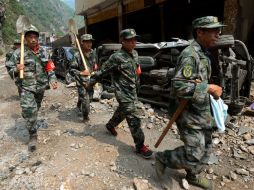 Rescatistas caminan frente a vehículos destruidos luego del terremoto. AFP  /