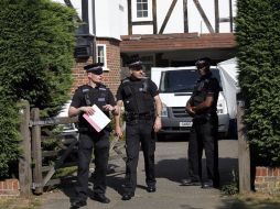 Policías británicos custodian hoy el acceso a la casa en Calygate, donde vivía la familia asesinada. EFE  /