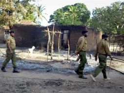 Policías caminan frente a casas quemadas durante los enfrentamientos. AP  /