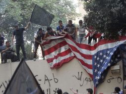 Los manifestantes escalaron el muro que protege la embajada, quitaron la bandera estadounidense y pusieron una bandera negra. EFE  /