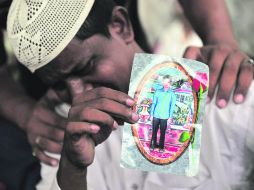 Un hombre llora la muerte de su hijo, cuya foto sostiene en la mano, en la ciudad de Karachi, Pakistán. AFP  /
