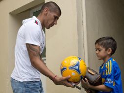 Carlos Salcido firma un balón a un pequeño aficionado de los Tigres. MEXSPORT  /