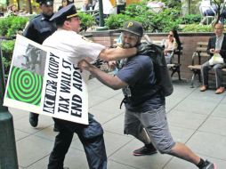 Desafío. Un manifestante forcejea con un oficial neoyorquino que intenta impedir que llegue a la entrada de la zona financiera. AP  /
