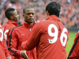 Suárez (de espaldas) estrecha la mano de Evra previo al partido del Liverpool contra el ManU. EFE  /
