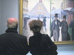 Un día lluvioso. Una pareja observa la pieza Rue de Paris, temps de pluie, de Gustave Caillebotte, en el Museo de Orsay. AFP  /