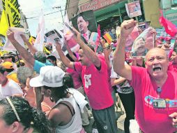 Partidarios del presidente de Venezuela, Hugo Chávez, muestran fotos del líder en un acto de campaña de Henrique Capriles. AP  /