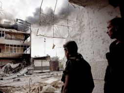 Rebeldes sirios esperan antes de cruzar una calle mientras intentan evadir a los francotiradores del ejército sirio. EFE  /