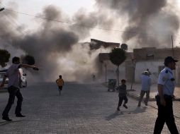 Unos ciudadanos turcos escapan del humo provocado por el estallido de una bomba de mortero lanzada desde Siria. EFE  /