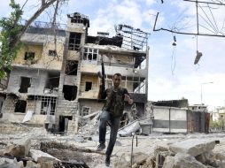 Un rebelde sirio corre a través de los escombros evitando a los francotiradores. AFP  /