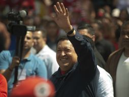 El presidente saluda a su llegada a la escuela en Caracas, donde sus partidarios le entregaron ramos de flores. AP  /