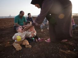 Una refugiada siria tiende su mano hacia unos niños en un campamento de personas desplazadas. EFE  /