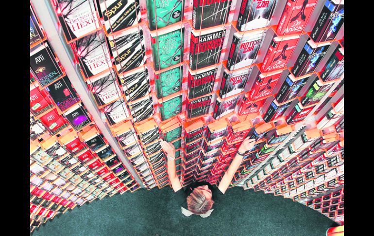 Una mujer coloca libros en un estante gigante antes de la inauguración de la más grande feria del libro del mundo, en Fráncfort. AP  /