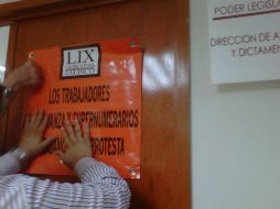 Trabajadores inconformes pegan carteles en las instalaciones del Congreso.  /