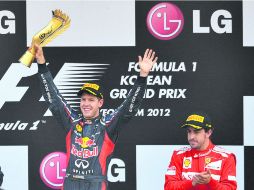 Opuestos. Vettel celebra en lo más alto del podio, mientras que Alonso hace lo posible por no hacer más evidente su frustración. AFP  /