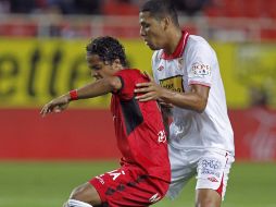 El centrocampista del Sevilla CF, Edwiges Maduro (d), lucha un balón con el mexicano Giovani Dos Santos, del RCD Mallorca. EFE  /