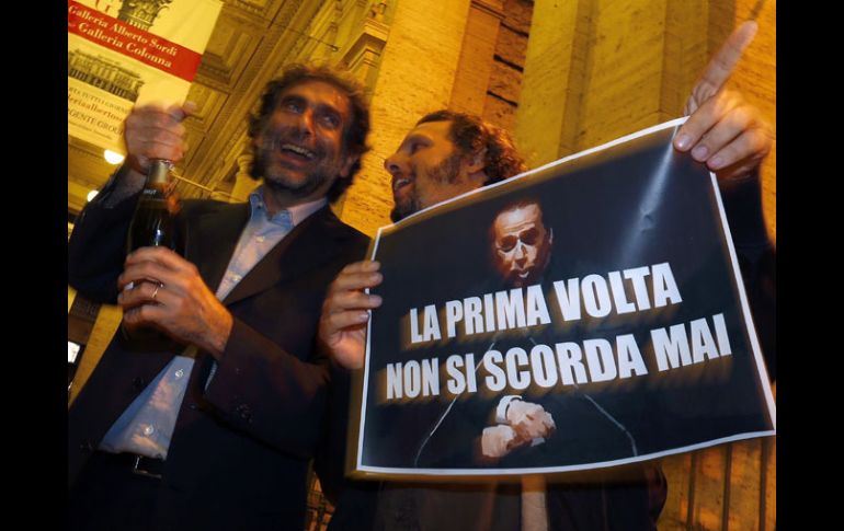 Manifestantes muestran un letrero que dice ''La primera vez nunca se olvida'', para celebrar la condena de Berlusconi. REUTERS  /