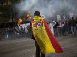 Un oficial de policía acude a la marcha con una bandera de España en su espalda. AP  /