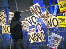 Un manifestante junto a una valla que protege al Parlamento de las protestas contra los recortes del presupuesto. AP  /