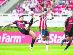 El capitán de los Rojinegros, Leandro Cufré, despeja el esférico ante la llegada del volante rojiblanco, Marco Fabián.  /