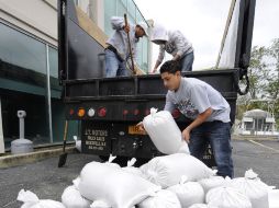 Empleados de un negocio en Nueva York descargan sacos de arena para colocar a la entrada, como medida de precaución. AP  /