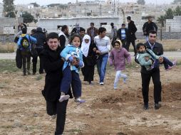 Varios sirios cruzan una alambrada mientras huyen de su país a Turquía. EFE  /