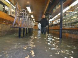 Un hombre dentro de un bar inundado en el centro de Venecia. EFE  /