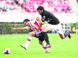 Freno de mano. Luis Pérez, de Chivas, y Christian Perellano, de Xolos, disputan un balón durante el partido de ayer en el Omnilife.  /