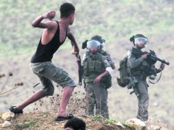 Un joven palestino lanza piedras contra soldados israelíes estacionados en la ciudad cisjordana de Nablus. AFP  /