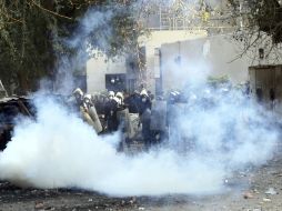 Agentes de policía antidisturbios egipcios, tratan de protegerse de los gases lacrimógenos. EFE  /