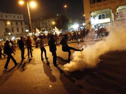 Los manifestantes patean una lata de gas lacrimógeno. AFP  /