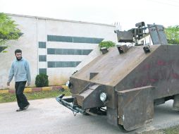 Equipo. Un ciudadano camina delante de un vehículo blindado casero hecho por la brigada de Al Ansar de los rebeldes, en Bishqatin. AFP  /