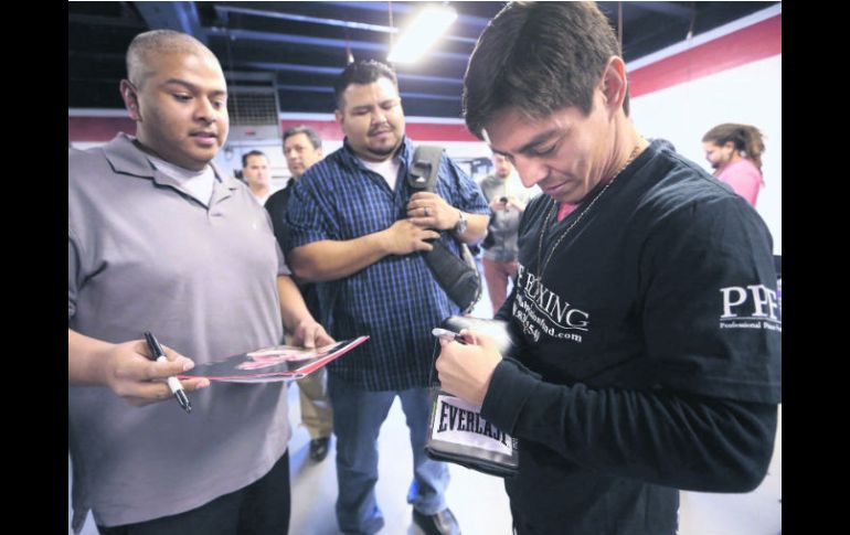 Complaciente. El púgil de Los Mochis, Jorge Arce, firma unos guantes a un aficionado. ESPECIAL  /