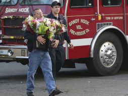 Bomberos colocan ofrendas florales en el lugar de la tragedia. AP  /