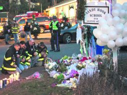 Dolor. Bomberos rezan frente a una ofrenda por las víctimas de la escuela primaria en Sandy Hook. REUTERS  /
