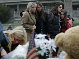 Mujeres se abrazan frente un altar improvisado para las víctimas de tiroteo en Newtown, Connecticut. AP  /