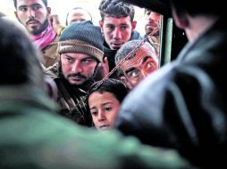 Causa bélica. Rebeldes sirios entregan pan a civiles en la ciudad de Idlib. AP  /