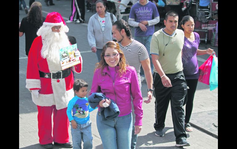 Comercio de temporada. Un Santa Claus ofrece a los transeúntes la tradicional fotografía navideña en el Centro tapatío.  /