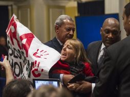 Una persona es retirada de la sala por un agente de seguridad después de interrumpir la comparecencia. EFE  /