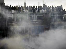 Decenas de comerciantes desesperados observan el humo provocado por el incendio. AP  /