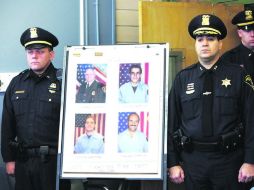 El policía Joseph Rieger posa junto a la foto de los bomberos muertos y heridos, en una conferencia de prensa. AP  /