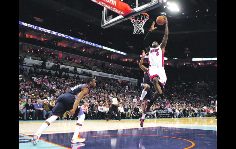Facilito. LeBron James se prepara para anotar, ante el intento de marca de dos defensas de los Bobcats. REUTERS  /