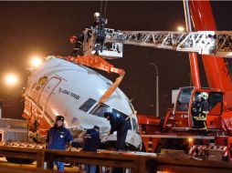 Una grúa despeja la autopista donde cayó parte del avión. XINHUA  /